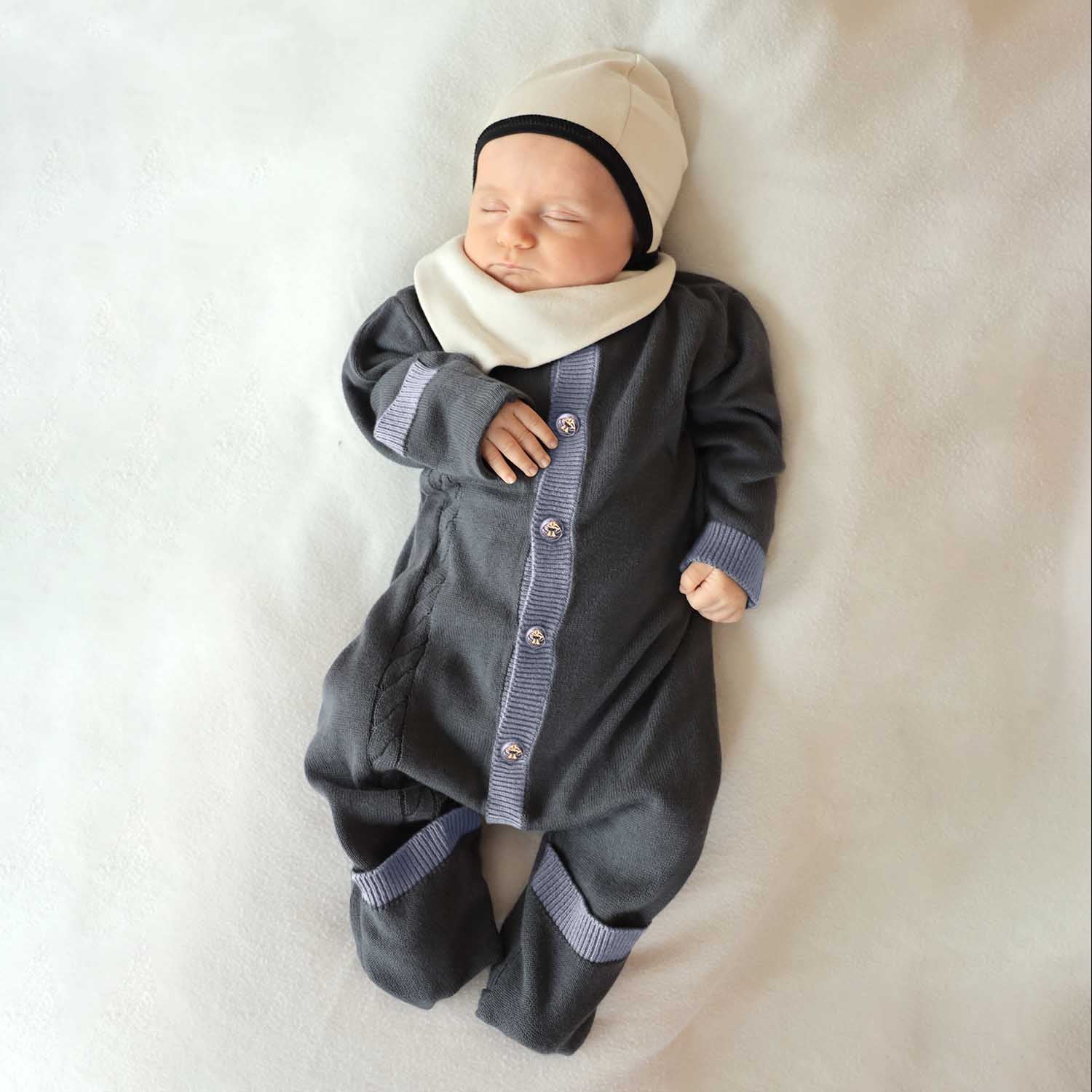Baby in a gray outfit with a white blanket