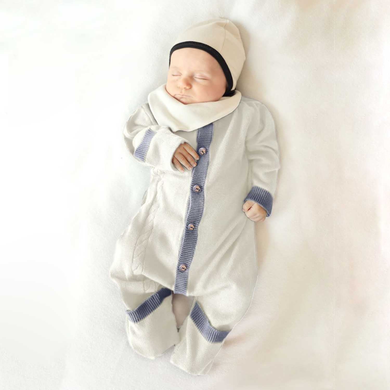 Newborn baby in a white outfit with blue accents on a white background